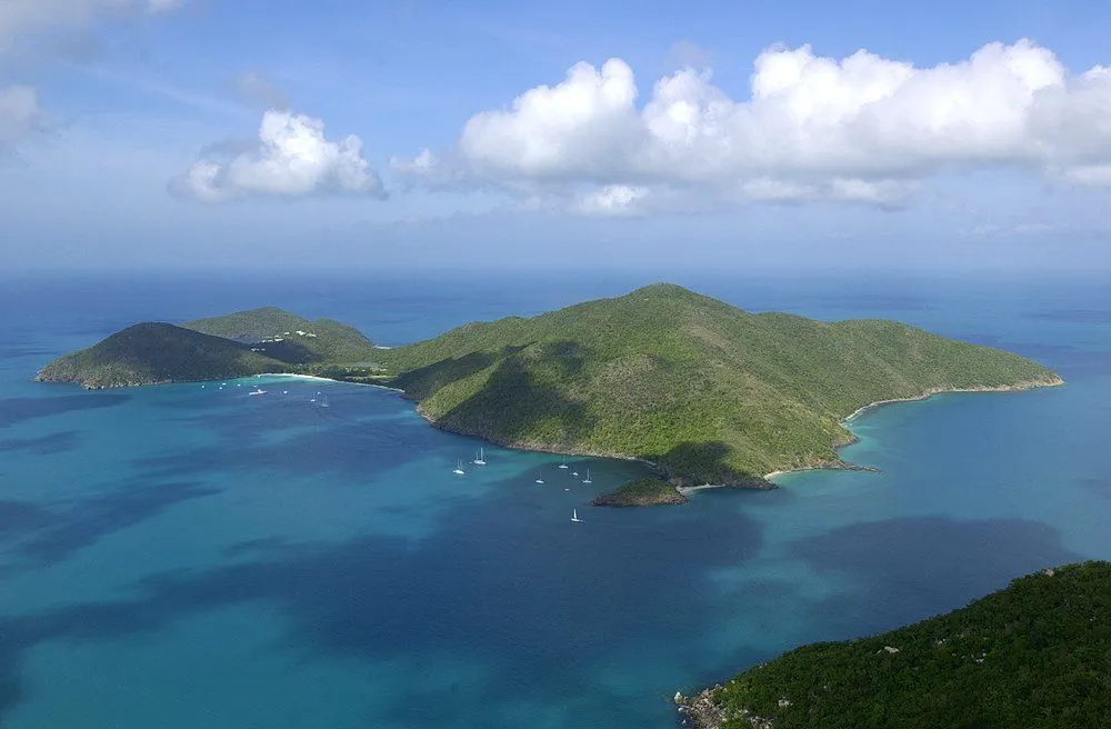 An aerial view of lush green islands in a clear turquoise bay with several sailboats.