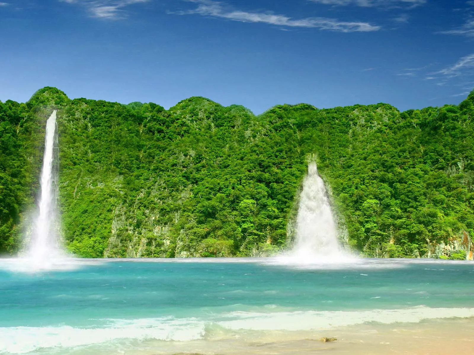 Two waterfalls cascade down lush green cliffs into a turquoise ocean with a sandy beach in the foreground.
