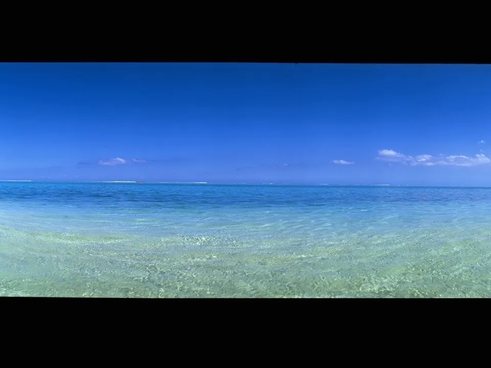 A panoramic view of a clear blue sky above shallow turquoise ocean waters.
