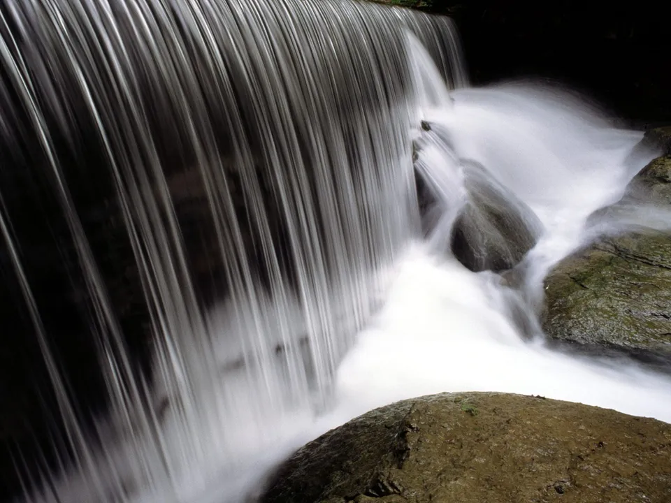 A long exposure shot of a waterfall cascading over moss-covered rocks.