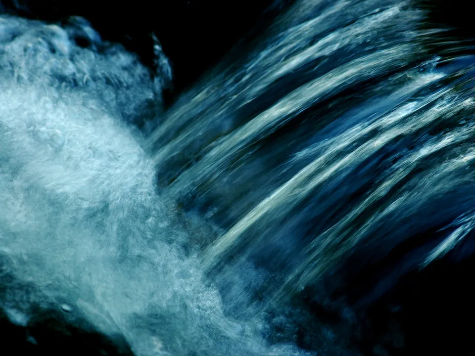 Close-up abstract view of water flowing and churning, with streaks of light and dark blue.