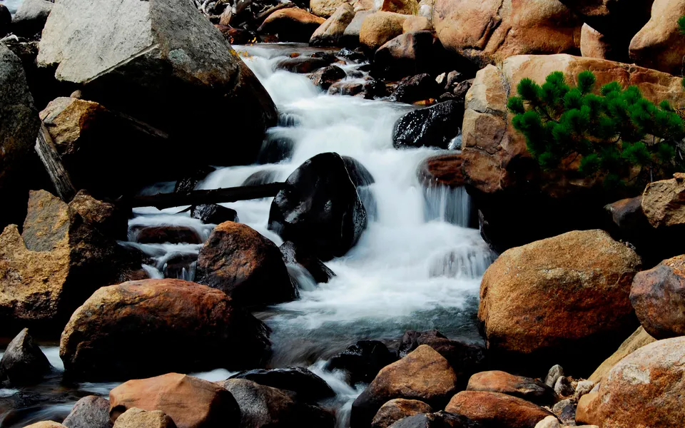 A close-up view of a waterfall cascading over large, smooth rocks in a rocky stream.