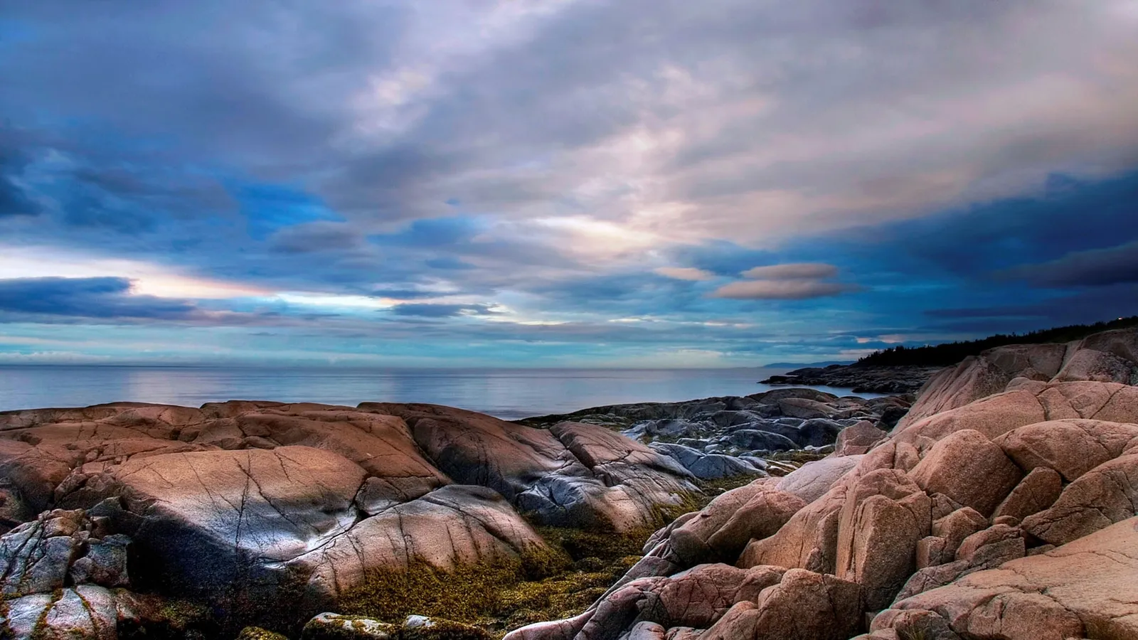 Rugged coastline with weathered rocks and a calm ocean under a dramatic sky.