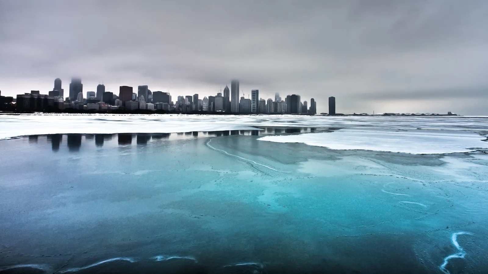 A city skyline is visible across a frozen lake with patches of blue ice.