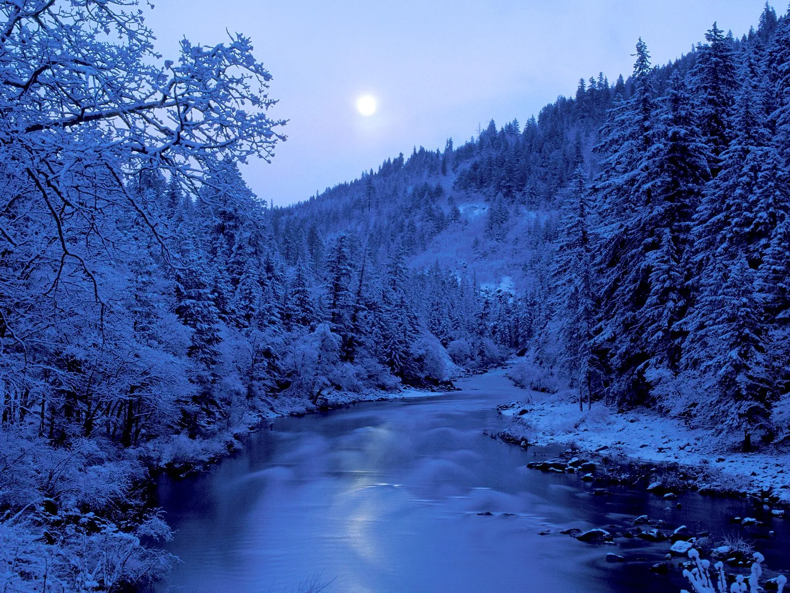 A wide river flows through a snow-covered forest under a pale moon.