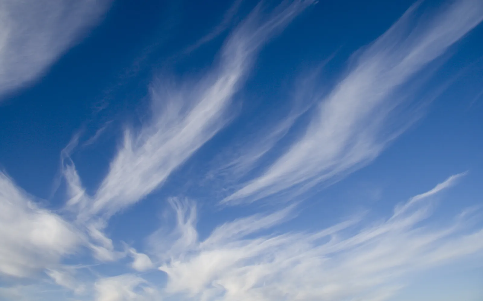 Thin, wispy cirrus clouds streak across a vibrant blue sky.