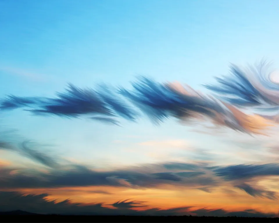 A sky filled with wispy, feathery clouds in shades of blue, orange, and pink during sunset.